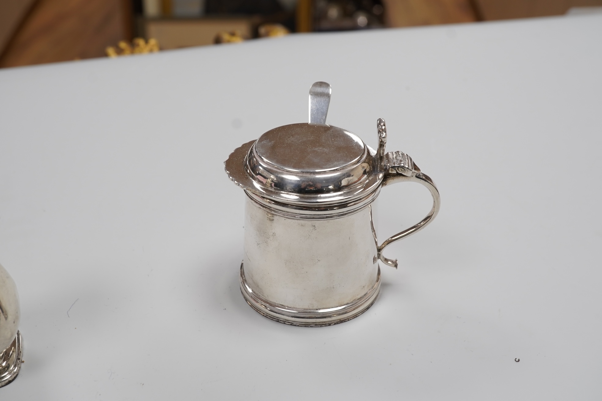 A George V silver drum mustard by Mappin & Webb, Birmingham, 1923, height 71mm, with associated spoon, together with a pair of George V silver pepperettes, Adie Brothers, Birmingham, 1923.